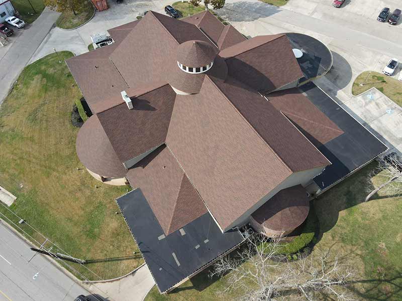 Top view of Neal Funeral Home's massive roof with new brown shingles installed by Broadway Roofing